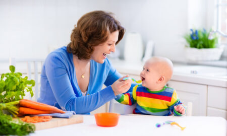 Mother feeding baby first solid food